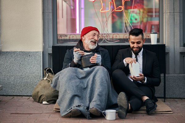 Homeless man and business man sitting down and having a happy conversation